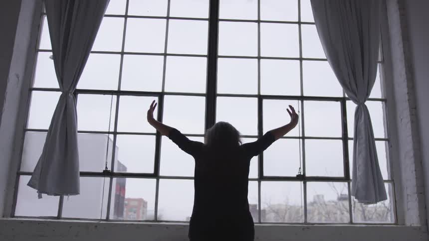 A woman dancing in front of a window at home