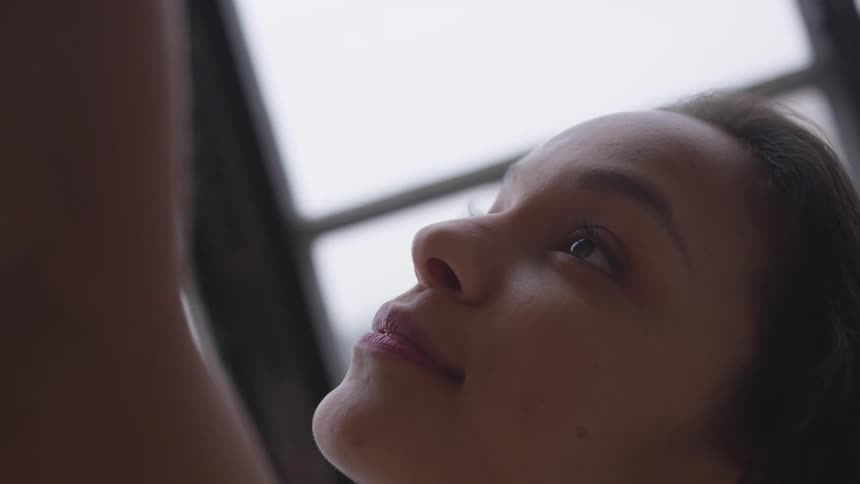 Sunlight shines through a window onto a dancer holding a pose