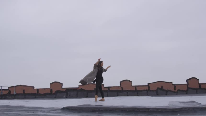 A woman dances on the roof as it snows