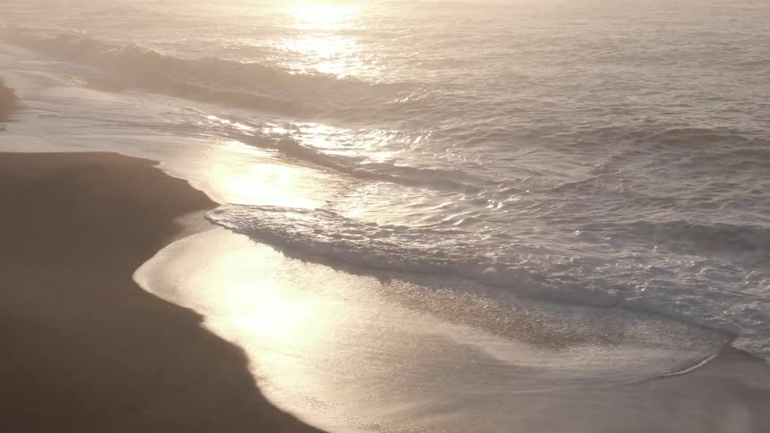 Ocean waves are moving next to the beach