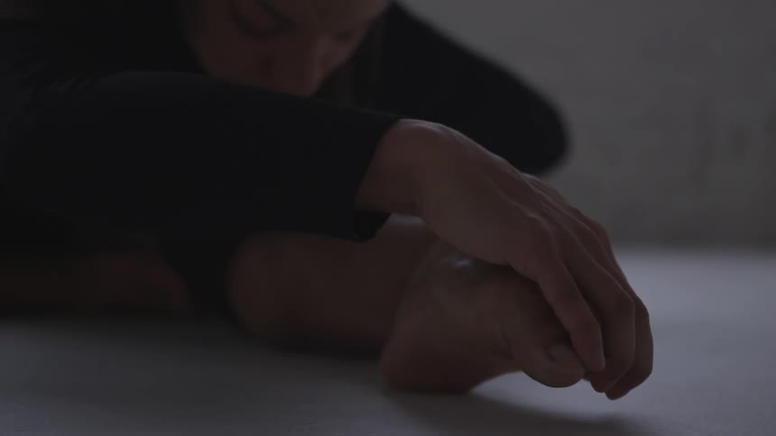 A woman leans forward and grabs her toes as she stretches