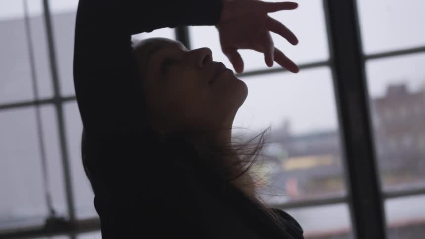 A woman is dancing in a building by a window