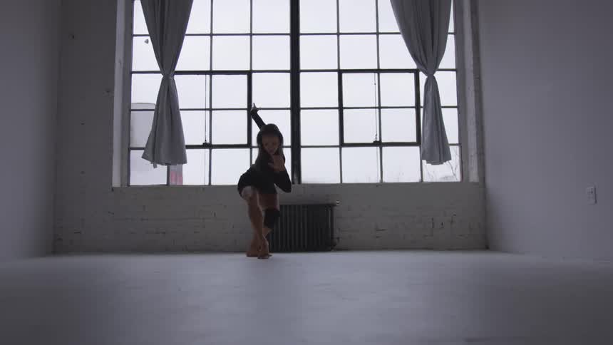 A woman is practicing ballet in a room
