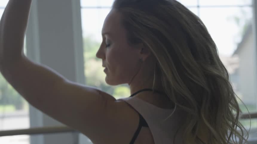 A young woman dancing in front of a window at home