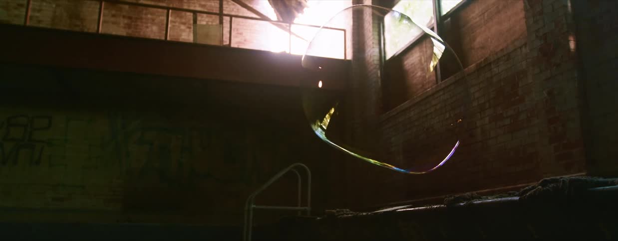 A large bubble floats in the air in a derelict pool building