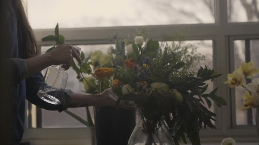 A woman sprays water onto a flower arrangement