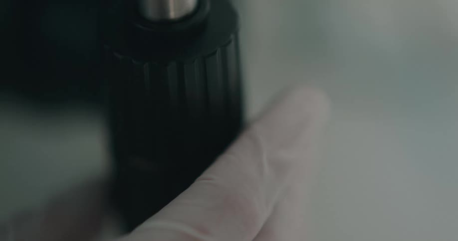 A persons hand with gloves turning a dial