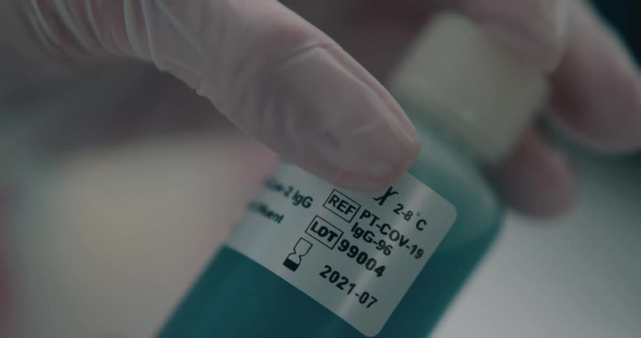 A gloved hand holding a bottle of covid treatment