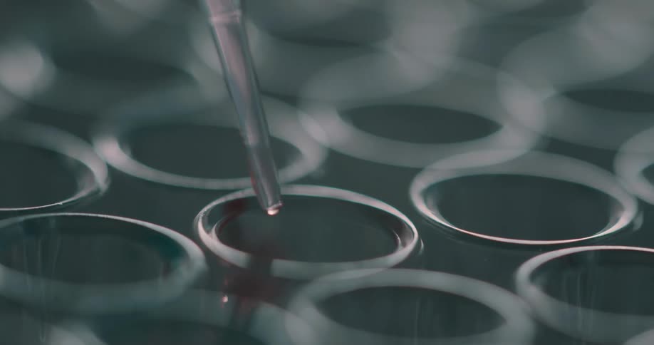 A tube dropping a liquid in a vial with light and reflection