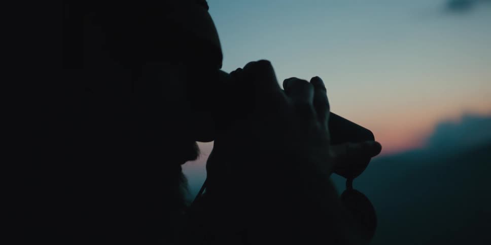 A man outside looks through binoculars