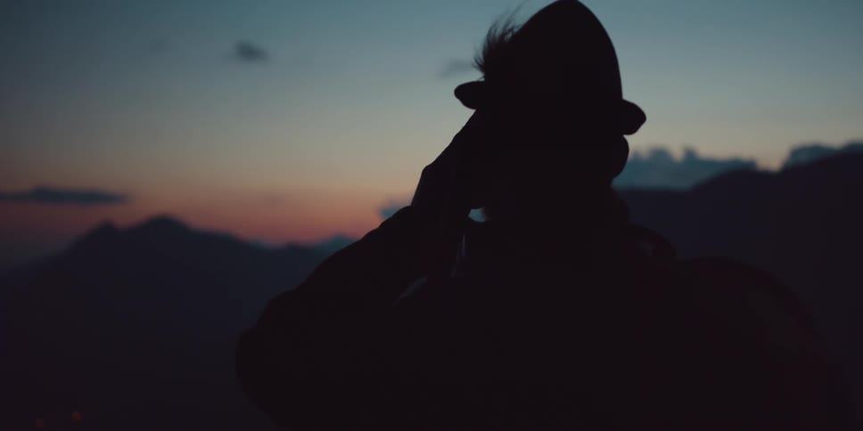 A man is standing outdoors at dusk