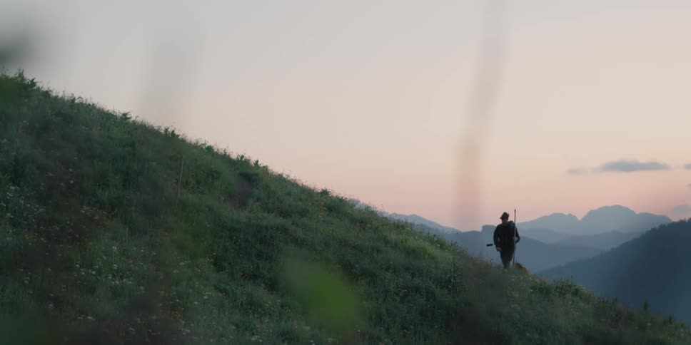 A man is hiking up a hill at dusk