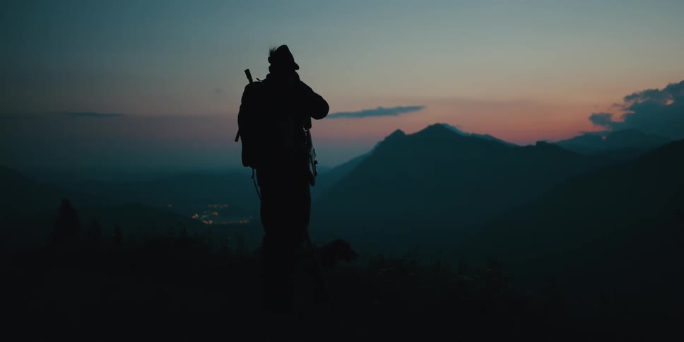 A man is hiking outdoors at dusk