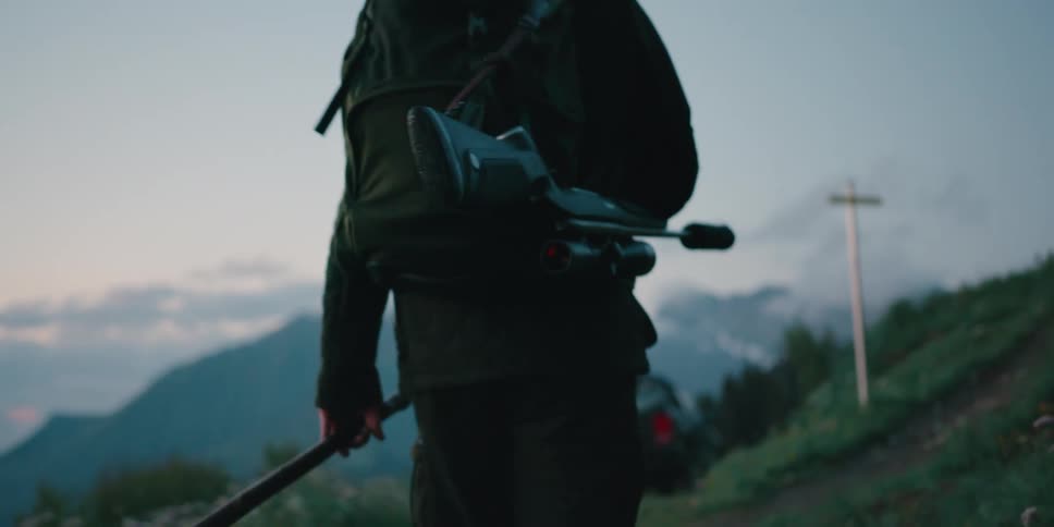 A man is hiking with a rifle