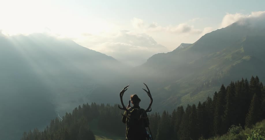 A man is looking at the landscape of a mountain at dusk
