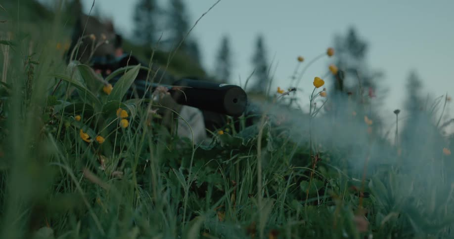 A hunter shooting his hunting rifle with a suppressor attached to it in slowmotion