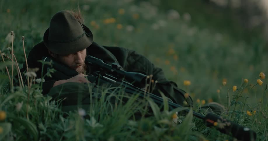 Man laying in field fires rifle