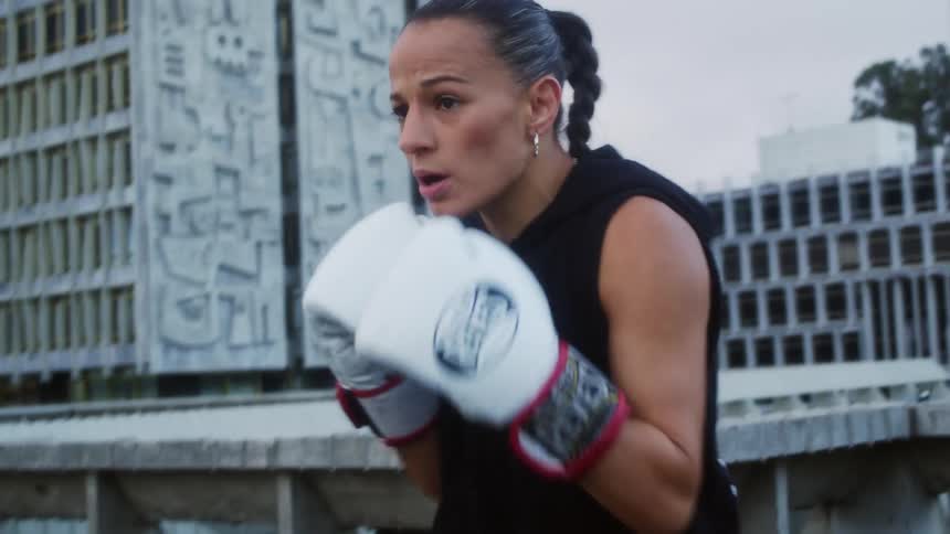 Woman wearing white boxing gloves practices outdoors