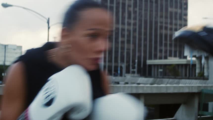 Two women boxing on a rooftop in a downtown area