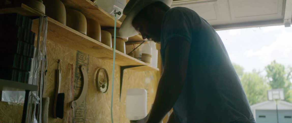 A man in his garage irons the brim of a hat