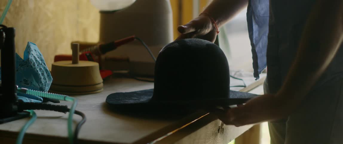A milliner making a cowboy hat in a small workshop