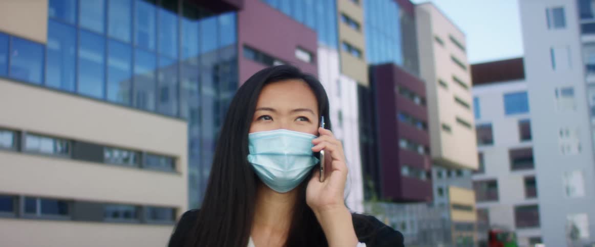A woman is wearing a face mask and talking on a cellphone