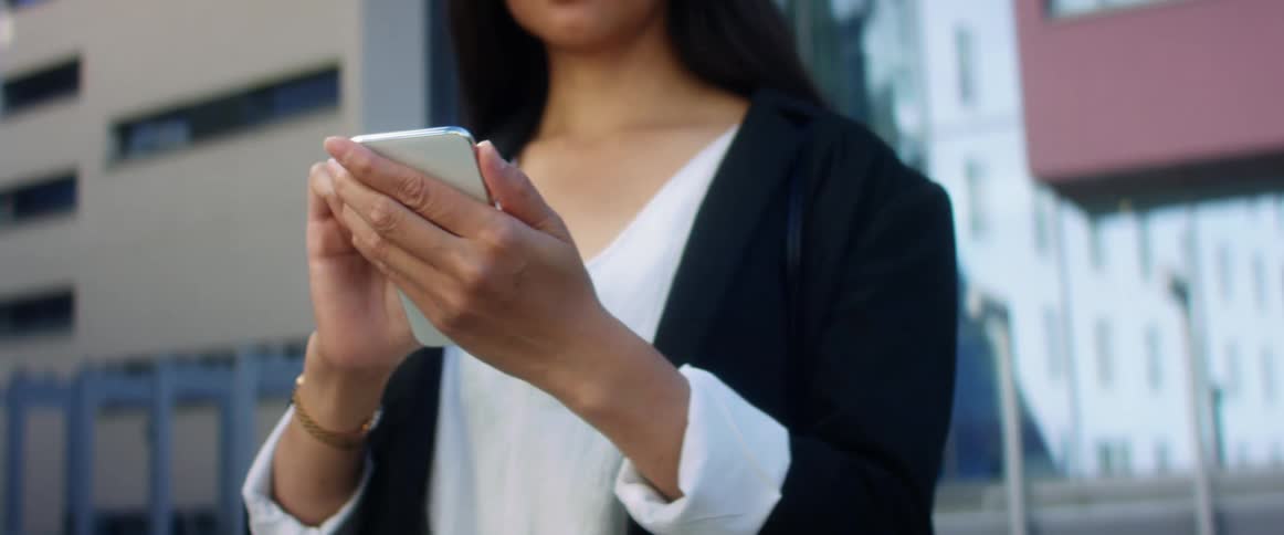 Young woman typing on cell phone outside office building
