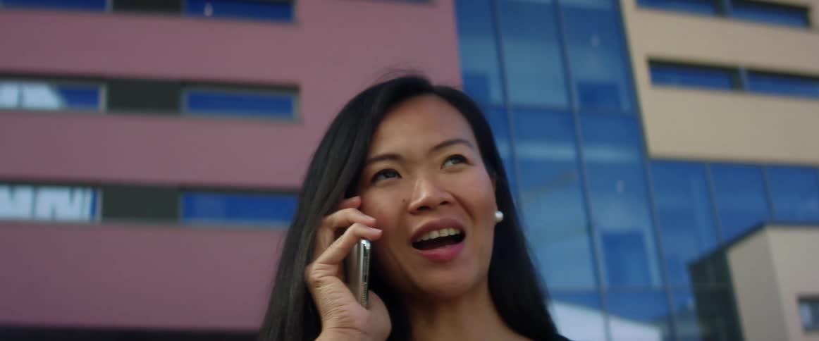 A woman talks on her cell phone in front of a large office buildings