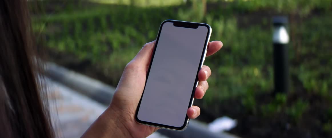 A woman is looking at a cell phone outdoors