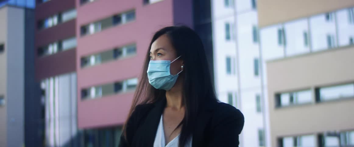 A woman is wearing a face mask in a downtown city