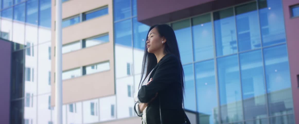 An asian woman is standing in a downtown city