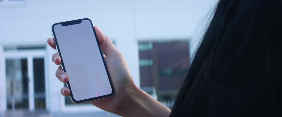 A woman holding a cell phone with a blank screen