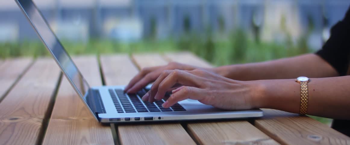 Woman sits at wood table uses macbook pro