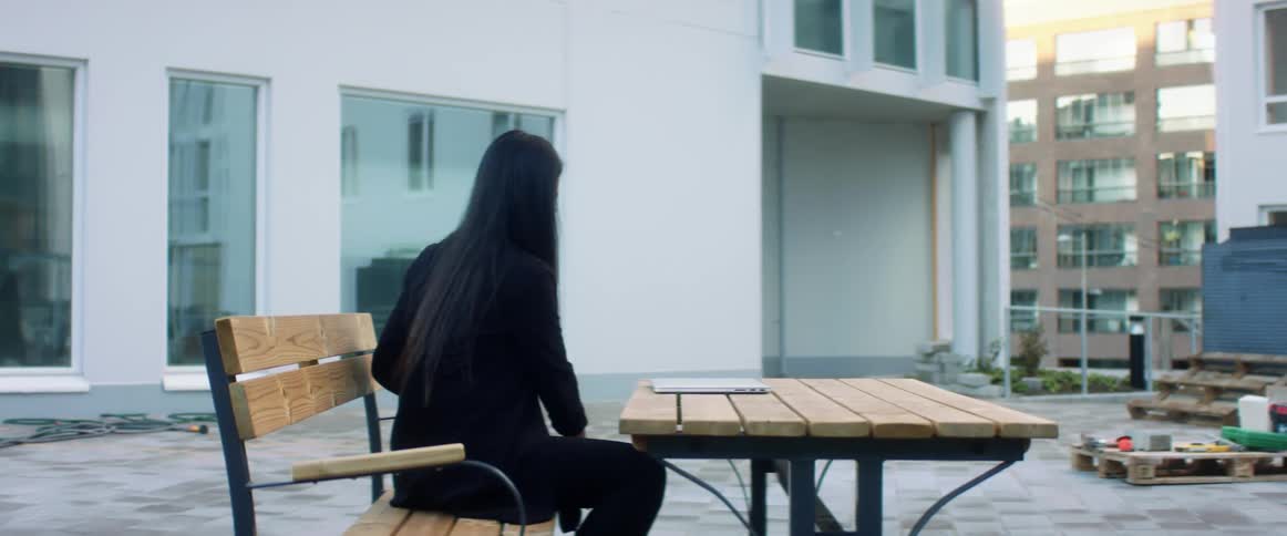 A woman sitting on a bench next to a table with a laptop