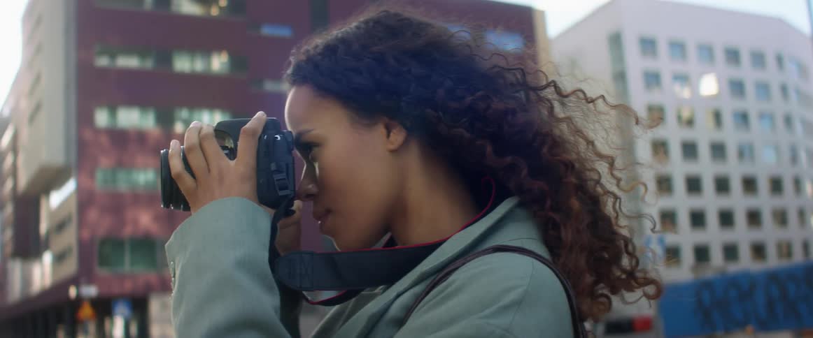 A woman is taking pictures with a camera in a downtown city