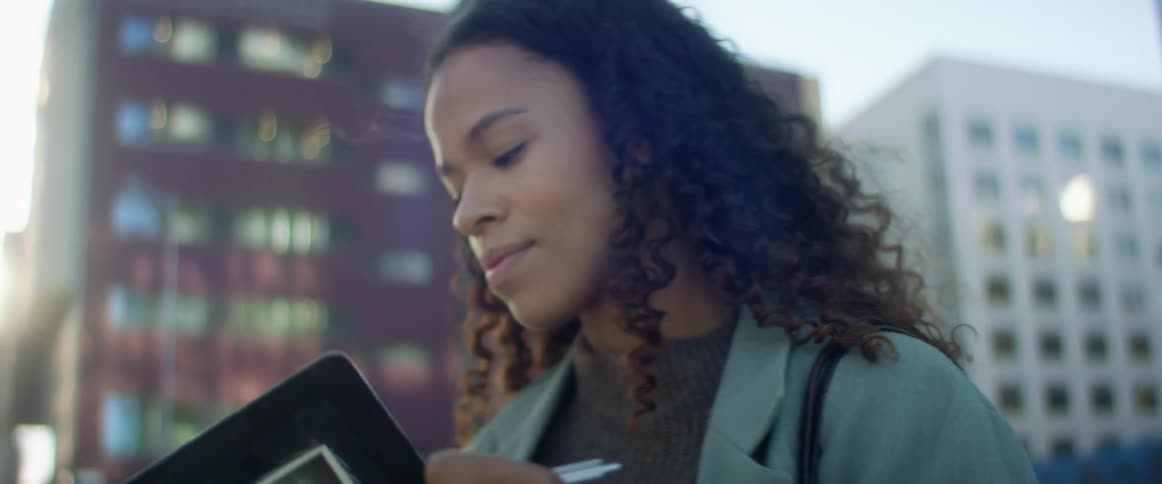 Woman takes notes on a notebook in the street of a city
