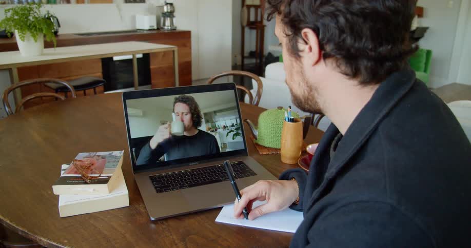 Two men at home video chat on a laptop