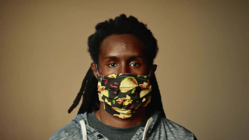 A man is wearing a face mask and standing next to a wall