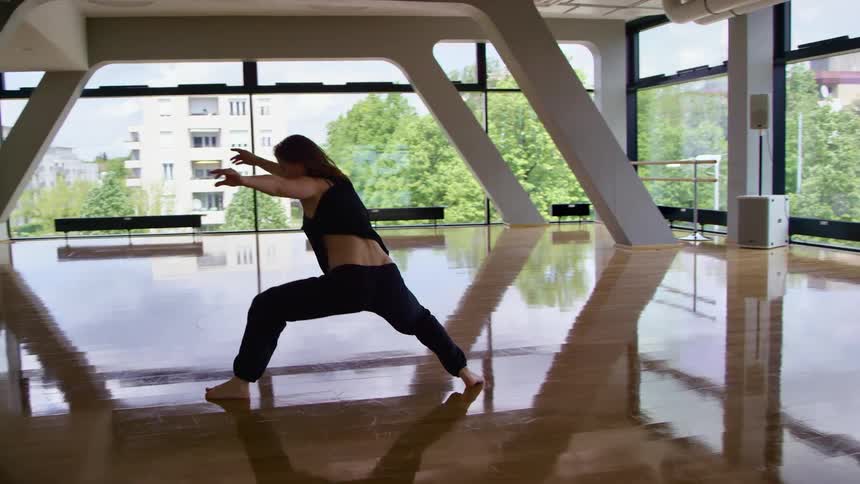 A young woman dances alone in an expensive dance studio in a city during the day