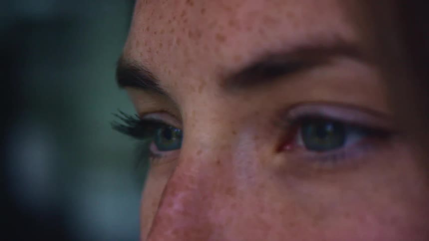Close up of a womans head with hazel eyes and freckles