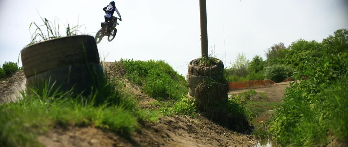 Man drives an off road motorcycle over the slope of a dirt race track