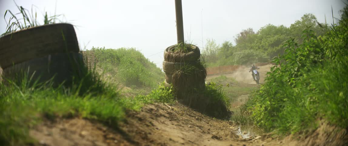 Man drives a dirt bike on a motocross track at day