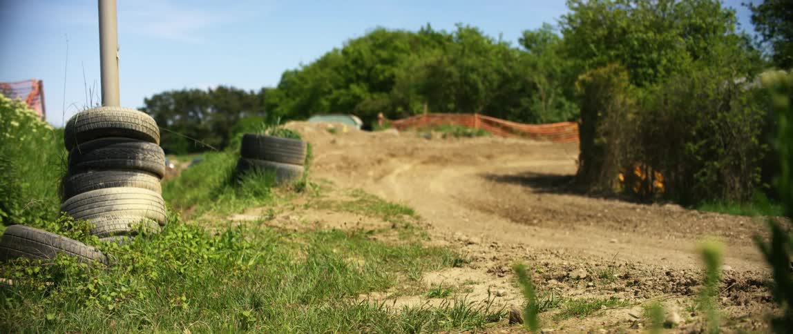 Stacks of tires are on the side of the dirt trail