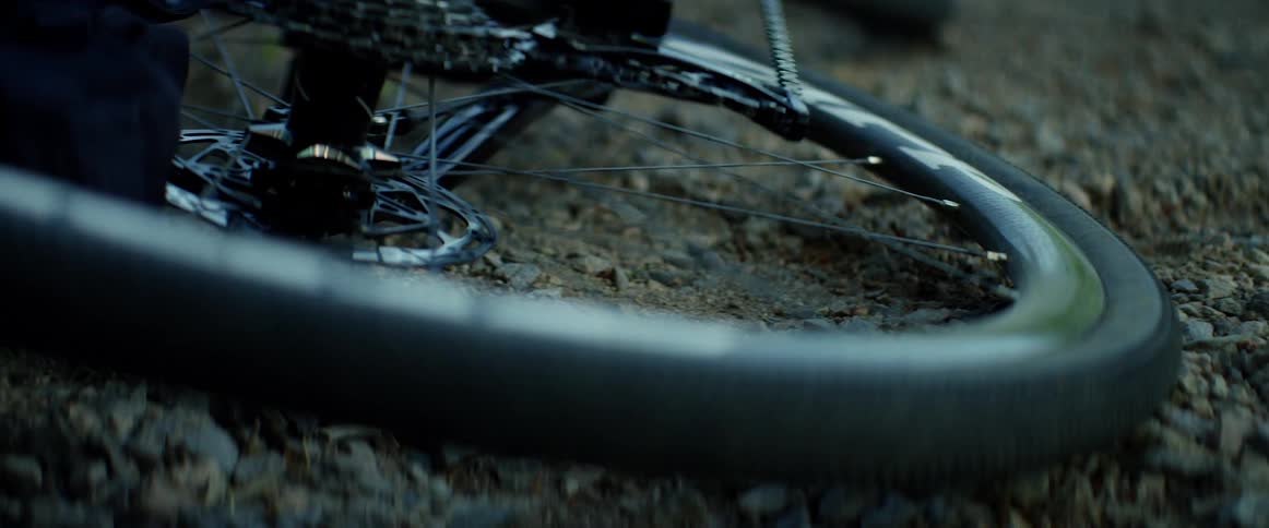 A bicycle rests on its side on gravel