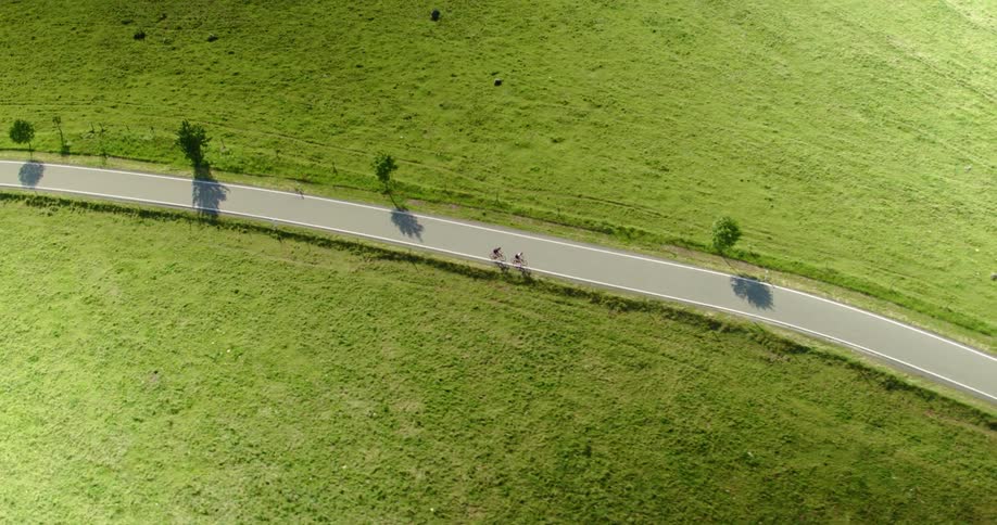 Aerial view of two cyclist riding on a grassland country road