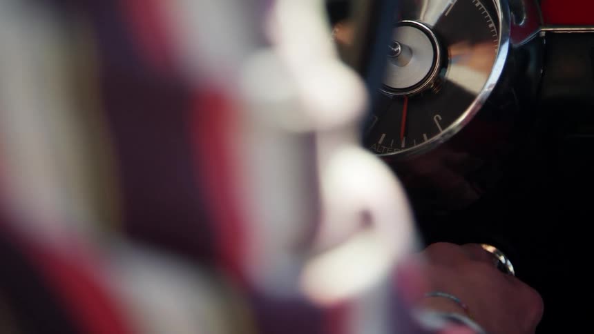 Very close shot of a mans arm as he puts a key in his vehicles ignition and turns it