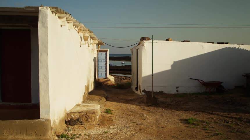 Simple small houses sit close together near a body of water in a village