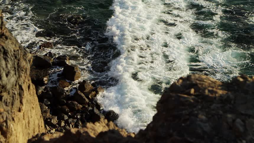 Ocean waves crashing into a rocky shoreline in the daytime