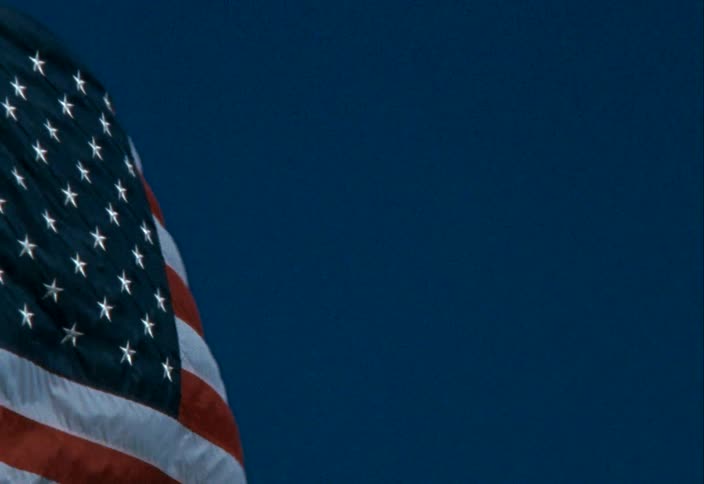 Close up of the american flag waving in the wind under a blue sky