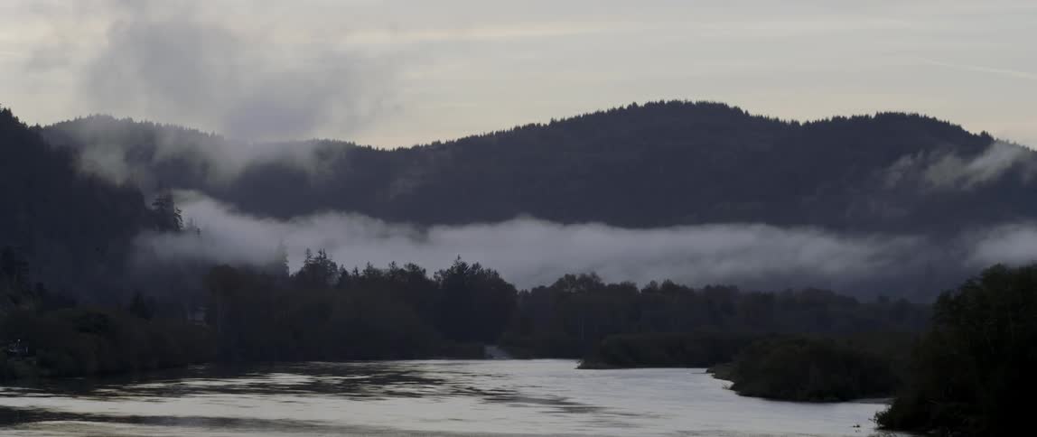 Fog rolls down a mountain near a lake